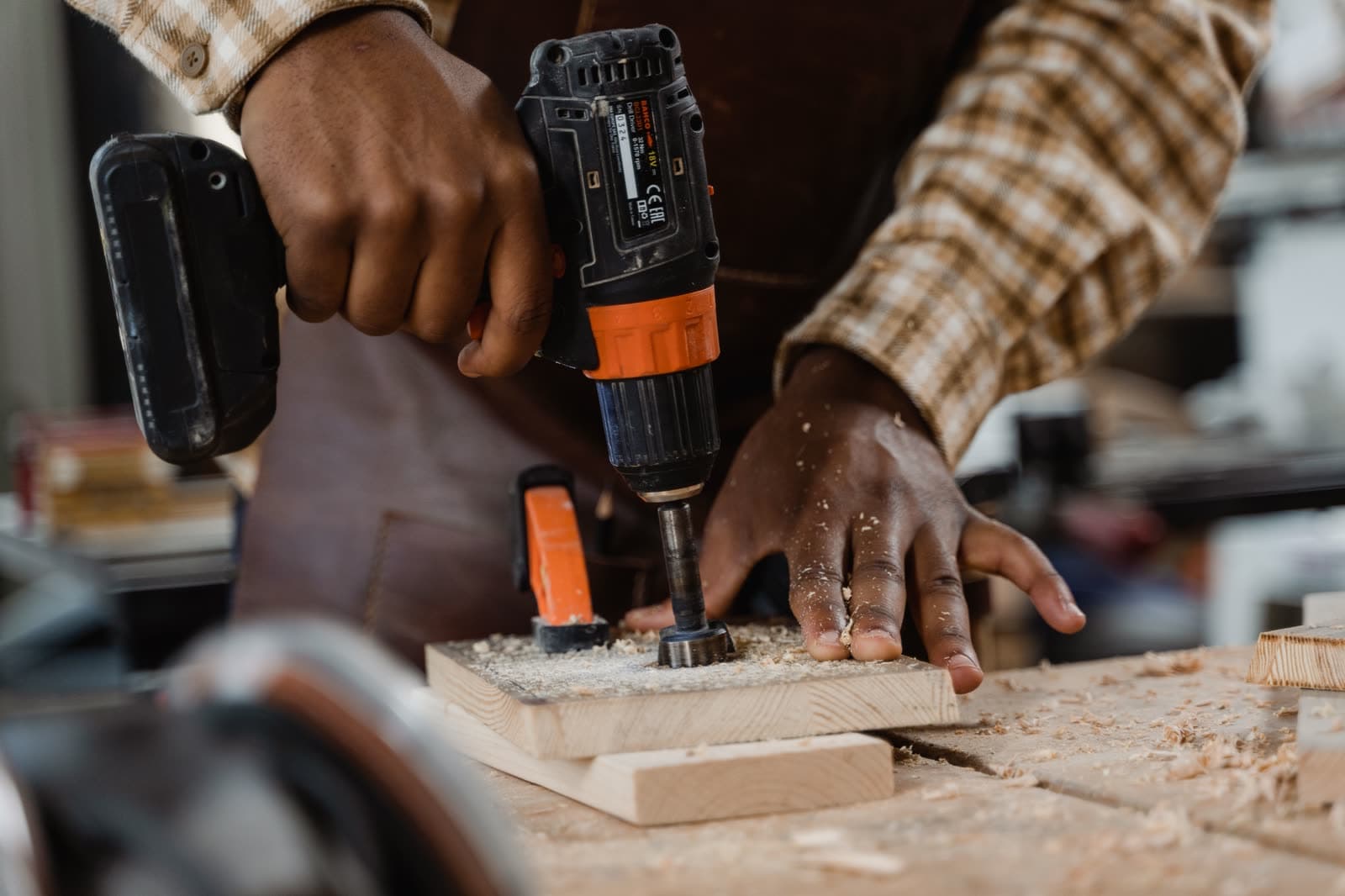 Hands drilling into a timber board with a cordless drill